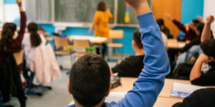 Schüler*innen sitzen in einem Klassenzimmer und melden sich