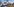 Eine rote Fahne weht auf einem Rundbau, davor halb abgerissene Gebäude, ein Bagger und ein Straßenschild