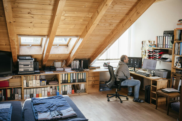 Ein Mann sitzt in einem Schlafzimmer an einem Schreibtisch Ein Mann sitzt in einem Schlafzimmer an einem Schreibtisch