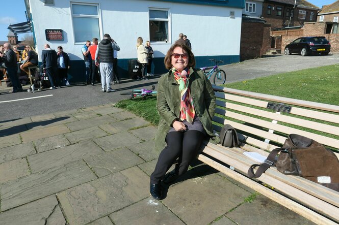 Frau mit Sonnenbrille sitzt auf einer Bank