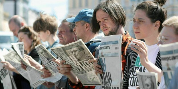 Demonstranten halten Zeitungen in den Händen.