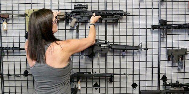 Eine Frau stellt eine Sig Sauer Waffe in ein Waffenregal