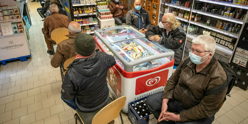 Um eine Eistheke sitzen Menschen, die auf Impfstoff warten