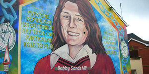 Ein Wandbild in Belfast in Nordirland zeigt Bobby Sands in rotem Pullover