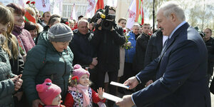 Lukaschenko reicht kleinen Mädchen ein Geschenk