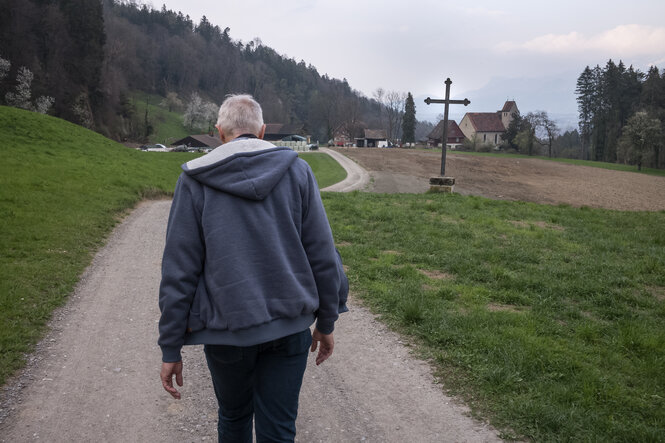 Louven von hinten auf einem Bergweg mit Kreuz am WEgesrand