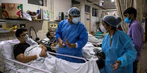 Krankenhauspersonal steht zwischen Coronapatienten herum und gestikuliert hektisch