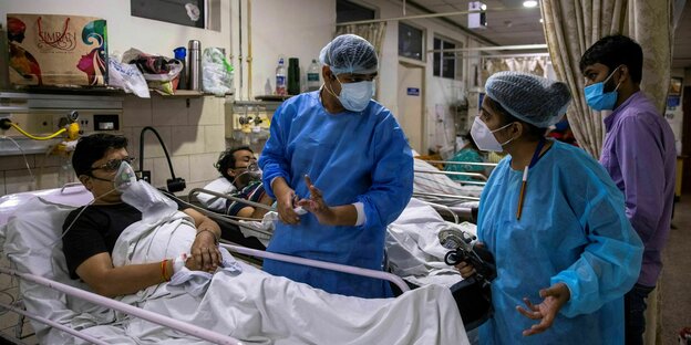 Krankenhauspersonal steht zwischen Coronapatienten herum und gestikuliert hektisch