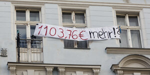 Anwohner haengen Transparente aus Fenster eines Hauses. auf dem Transpaent steht: "1103 Euro mehr"
