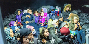 Auf einem Frontexboot sitzen eine Gruppe Menschen