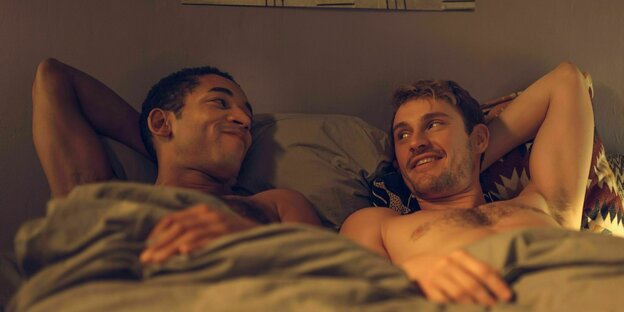 Zwei Männer liegen im Bett.