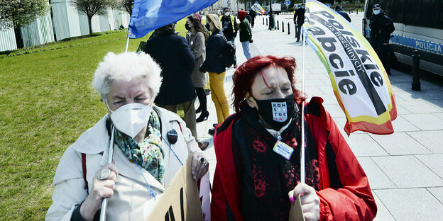 Zwei Frauen stehen mit Fahnen vor dem Gerichtsgebäude in Warschau