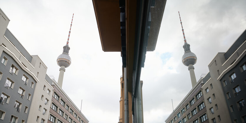 Der Fernsehturm und ein Wohnhaus spiegeln sich in einer Glasfassade