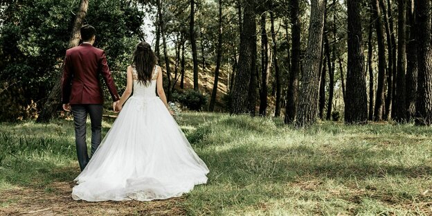 Spaziergang im Wald: ein Hochzeitspaar hält sich an den Händen