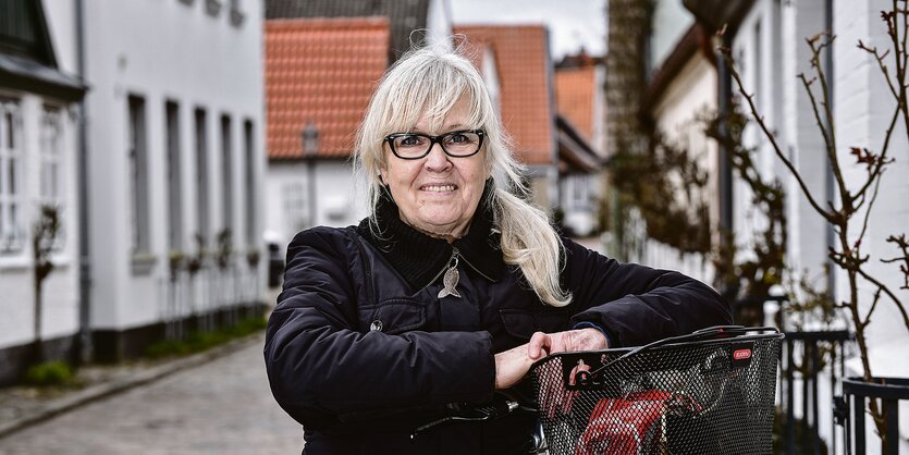 Marlies Jensen-Leier steht mit ihrem Fahrrad in einer Straße.