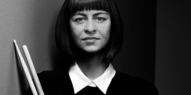 Schwarz-weiß Porträt der Schlagzeugerin Katharina Ernst. Die Künstlerin hält ihre Drumsticks in den Händen