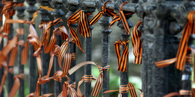 Um Zaun gebundene schwarz-orangene Bänder