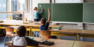 Zwei Schüler sitzen mit Leherin in einem Klassenraum