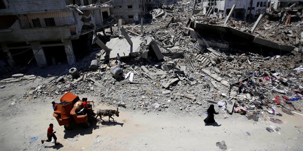 Menschen laufen durch Ruinen in Gaza-Stadt.