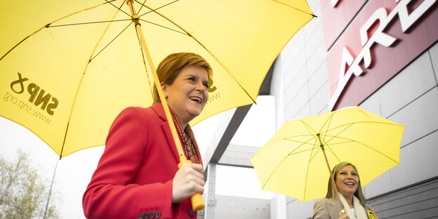 Nicola Sturgeon, Erste Ministerin von Schottland, lachend mit gelben Sonnenschirmen mit dem SNP-Parteilogo