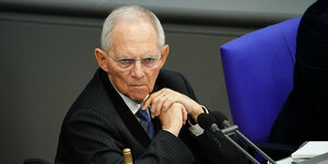 Wolfgang Schäuble sitzt im Bundestag im Rollstuhl vor einer grauen Wand im Bundestag