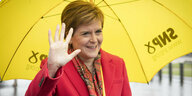 Nicola Sturgeon grüßt unter gelbem Sonnenschirm