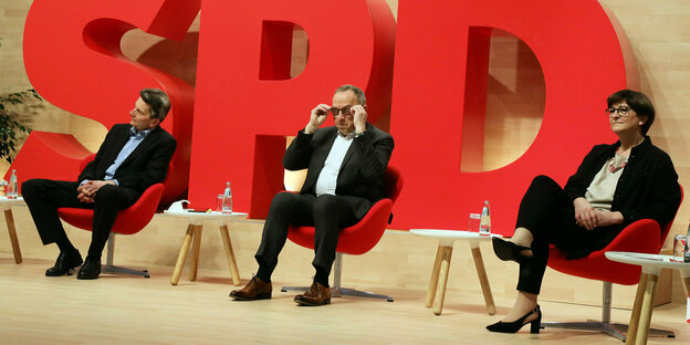 Rolf Mützenich, Norbert Walter-Borjans und Saskia Esken sitzen auf Sesseln vor einem SPD Logo