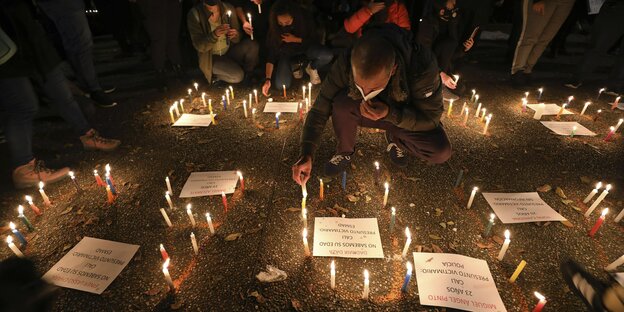Teilnehmer einer Mahnwache für die während der regierungskritischen Proteste Verstorbenen zünden Kerzen an.