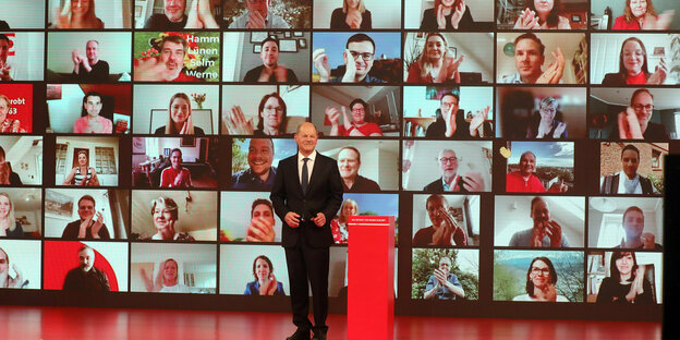 Olaf Scholz, Bundesfinanzminister und Kanzlerkandidat der SPD, lächelt vor einer virtuellen Wand mit zoom-Gesichtern