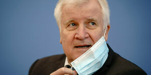 Horst Seehofer beim Abnehmen seines Mundschutzes bei einer Pressekonferenz