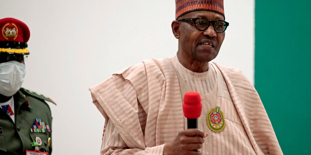 Nigerias Präsident in traditionellem Gewand mit einem Mikrofon in der Hand