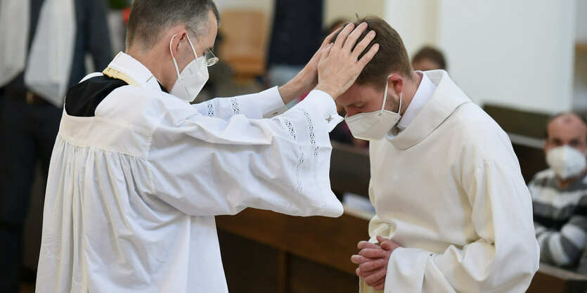 Ein Pfarrer hält bei einem Open-Air-Segnungsgottesdienst für Liebende vor der Kirche Christi Auferstehung einen Kelch - Hintergrund ist eine Regenbogenfahne zu sehen