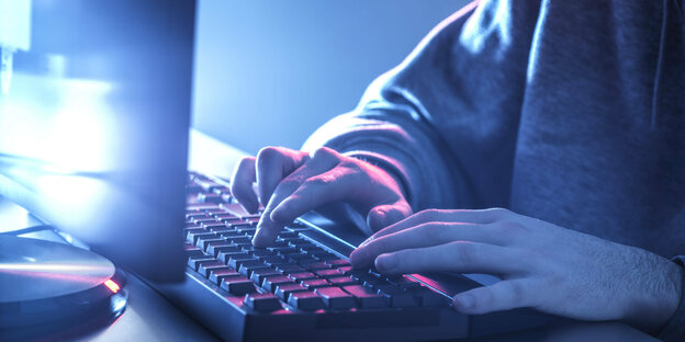 Mann vor Computermonitor - Hände an einer Tastatur