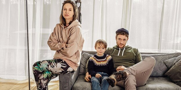 Eine Mutter mit ihrem Sohn und Vater sitzen auf einem Sofa in der Serie „Schlafschafe“