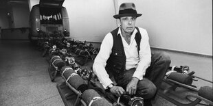 Schwarz-weiß Fotografie des Künstlers Joseph Beuys beim Aufbau einer Installation