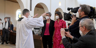 Ein Priester segnet zwei Frauen in einer Kirche