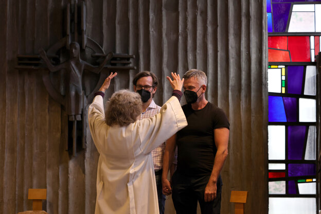Pfarrerin segnet zwei Männer in einer Kirche