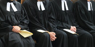 Vier Priesteramtskandidaten sitzen auf einer Kirchenbank - man sieht ausschließlich ihre Talare