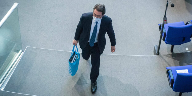 Verkehrsminister Andreas Scheuer läuft durch den Bundestag mit Stofftasche