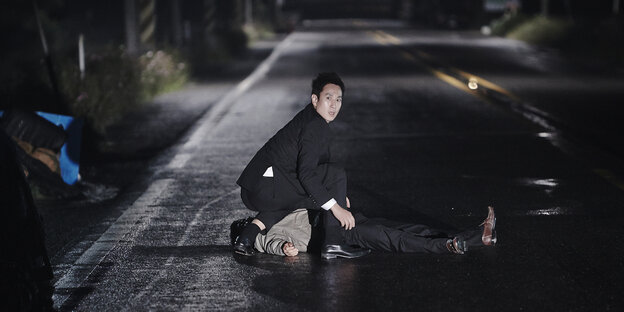 Der korrupte Polizist Gun-su kniet nachts über seinem Unfallopfer auf der Straße.