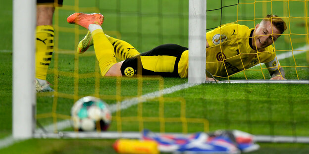 Marco Reus freudestrahlend neben dem Außenpfosten am Boden, der Ball im Tor
