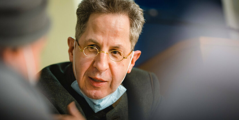 Hans-Georg Maaßen im Gespräch mit Mundschutz unter demKinn