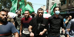 Männer tragen Flaggen der Hamas und einen Sarg durch die Straßen