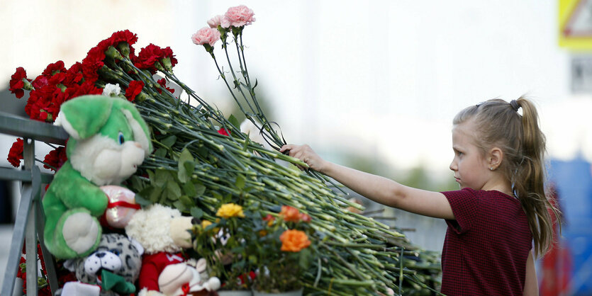 Ein Mädchen legt Blumen nieder