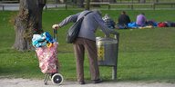 Eine Frau sammelt Pfandflaschen in einem Park in München