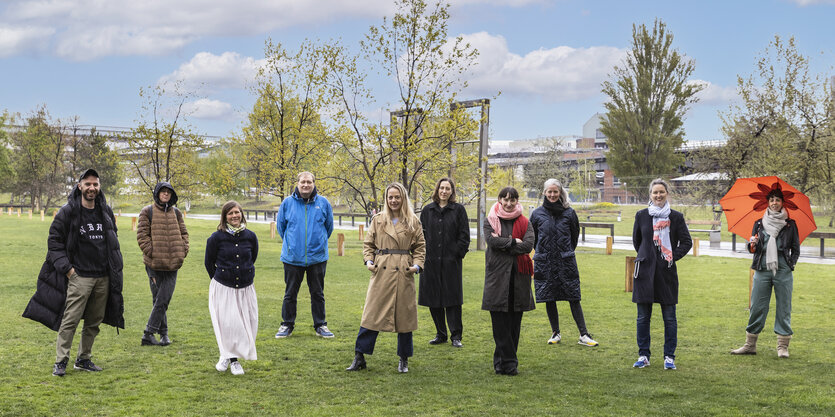 Zehn Frauen und Männer stehen in einem Park