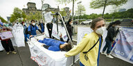 Eine Demonstrantin und ein Demonstrant mit einem Krankenhausbett