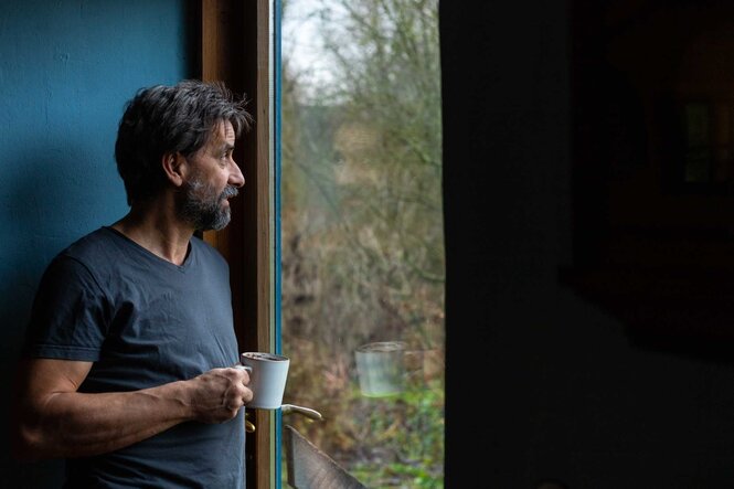 Olaf Schnelle schaut mit einer Tasse in der Hand aus dem Fenster