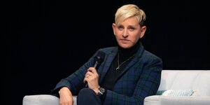 Ellen DeGeneres sitzt mit einem Mikro in der Hand auf einem Sofa