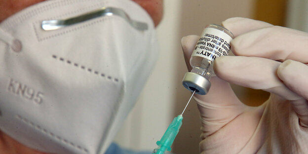 eine Ärztin zieht eine Spritze mit Coronaimpfstoff auf